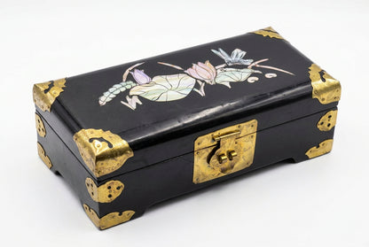 Boîte à bijoux chinoise noire fermée sur fond blanc, décor de lotus et de libellule et ornements métalliques dorés