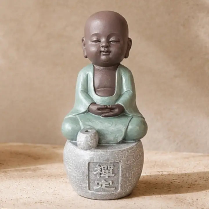 Figurine porte-encens de petit Bouddha en tenue vert clair, les mains posées sur les genoux, sur un socle gris